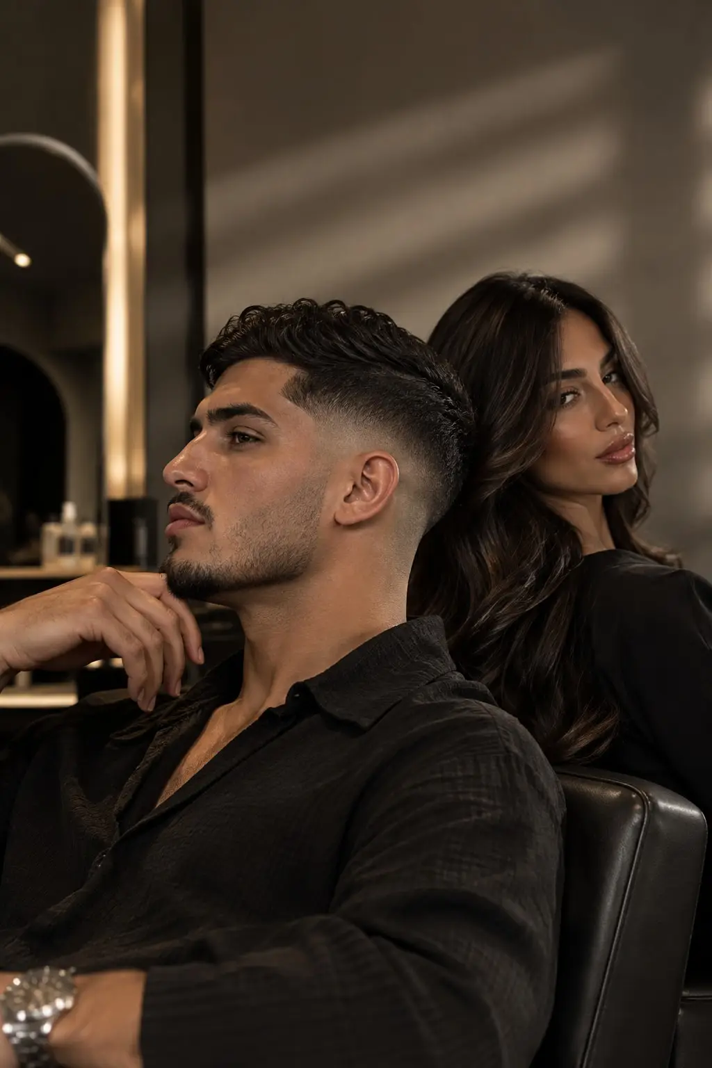 Un homme et une femme installés dans des fauteuils en cuir noir, dans un salon aux lumières chaudes